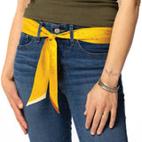 A person in blue jeans and a green top styles the Jenni Earle "This Ain't My First Rodeo" Silk Twilly Scarf as a belt, accessorizing with a bracelet, ring, and displaying a tattoo on their left hand.