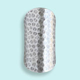 The Silver Cigar Band Ring by Ornamental Things, featuring a wide, rectangular design with a hammered texture, is shown against a light blue background.