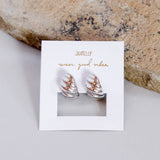 The JaxKelly Silver Hoop Swirl Earrings—tarnish-free, hypoallergenic silver hoops—are shown on a branded "wear good vibes" card beside a light stone. Perfect for sensitive ears.