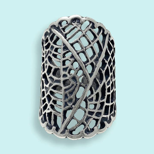 The Silver Leaf Lace Ring by Ornamental Things features an intricate dried leaf pattern with scalloped edges in sterling silver on a light blue background.