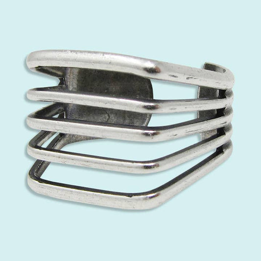 The Silver Line Ring by Ornamental Things features four parallel sterling silver bands with open spaces, shown against a light blue background.