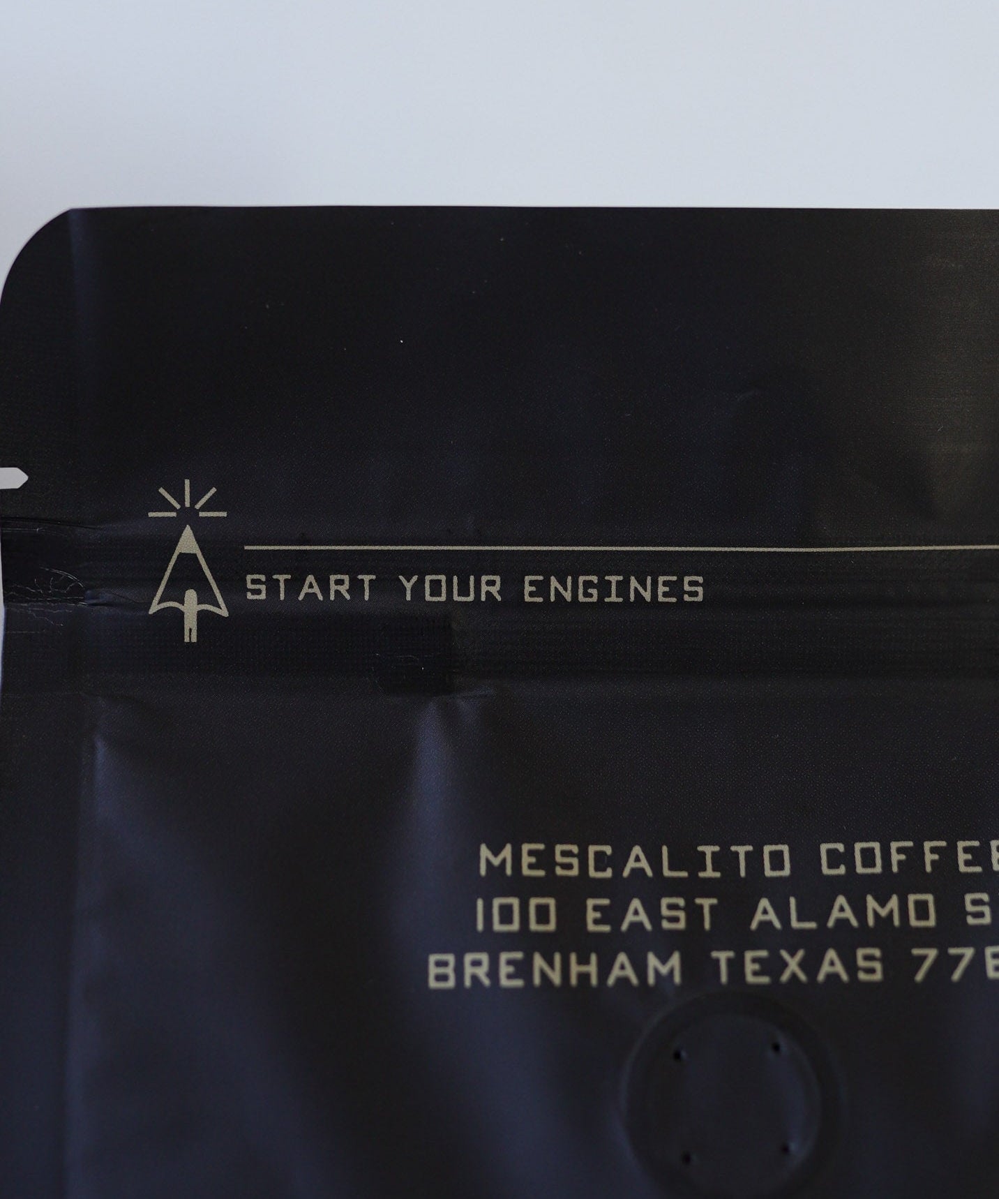 A bag of Mescalito Coffee's Single Origin Whole Coffee Beans | Chelchele displays "START YOUR ENGINES" at the top and an address in Brenham, Texas below—this medium roast showcases the unique flavors of Ethiopian coffee.