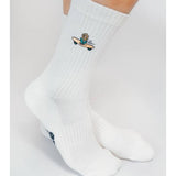 Wearing Tailored Union’s Skateboard Sunflower Knit Crew Sock by Loindaflow, these white crew socks showcase a small embroidered Skateboard Sunflower design near the ankles.