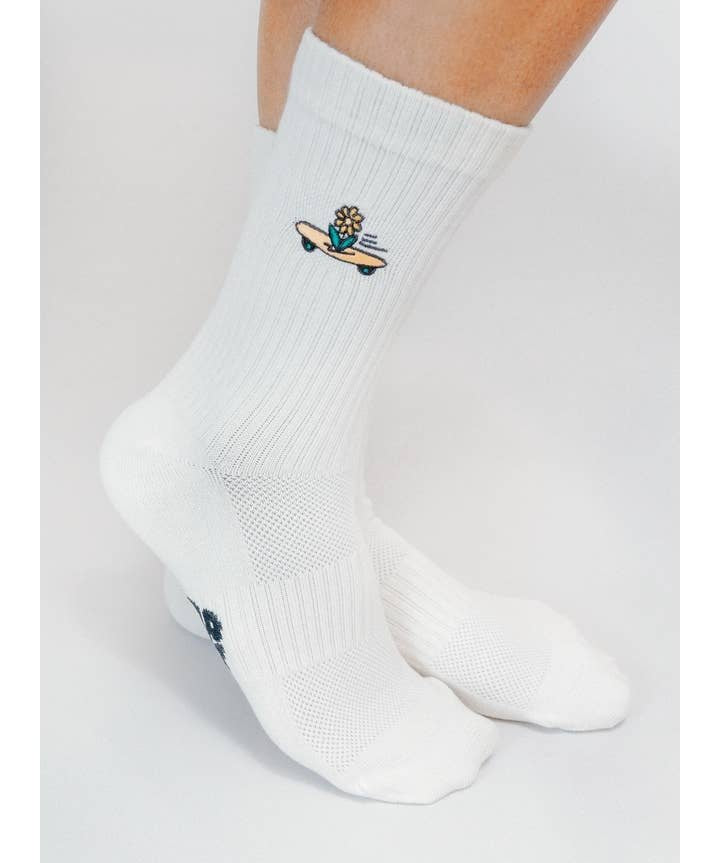 Wearing Tailored Union’s Skateboard Sunflower Knit Crew Sock by Loindaflow, these white crew socks showcase a small embroidered Skateboard Sunflower design near the ankles.
