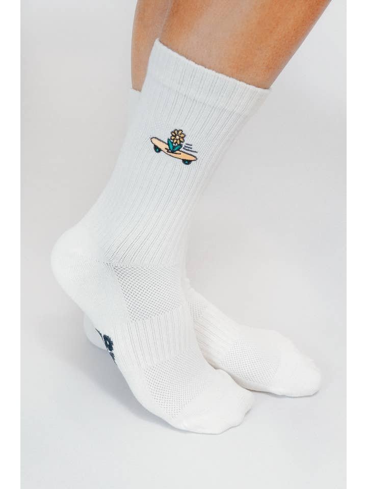 Wearing Tailored Union’s Skateboard Sunflower Knit Crew Sock by Loindaflow, these white crew socks showcase a small embroidered Skateboard Sunflower design near the ankles.