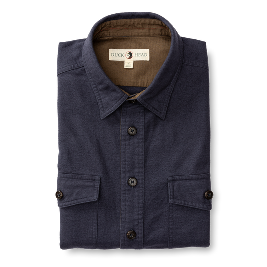 The Slater Moleskin Overshirt by Duck Head is a neatly folded navy blue shirt with two front pockets and a signature label on the collar, adding rugged style to your wardrobe.