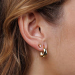 Close-up of a person's ear wearing Small Ripple Gold Hoop Earrings by JaxKelly—hypoallergenic, tarnish-free jewelry.