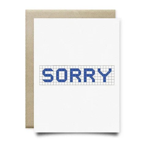 Sorry | Anvil Cards by Anvil Cards: A2 greeting card with "SORRY" in blue block letters on a white grid linen paper, paired with a brown envelope. Blank inside—ideal for sincere apologies.