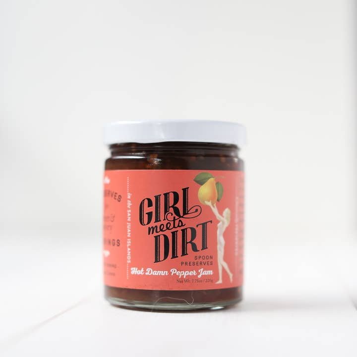 A jar of Spoon Preserves by Girl Meets Dirt features an artisanal organic fruit jam with a pink label showing a woman holding a peach.