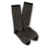 The Striped Logo Sock by Duck Head features black fabric with white horizontal stripes and a small embroidered Duck Head logo near the top, made in the USA.