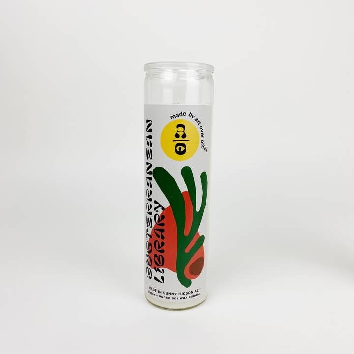 A white cylindrical vegan candle by Art Over Order, labeled "Subterranean Library Intention Candle," features abstract green and red designs, a circular top logo, and an earthy scent—ideal for relaxation or as a unique prayer candle.