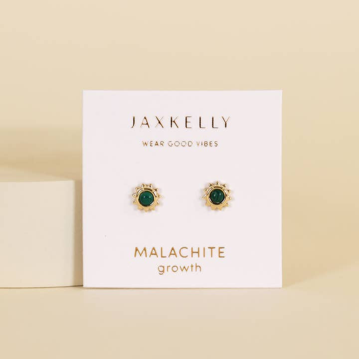 A pair of Sun Stud Earrings by JaxKelly, featuring gold-rimmed green malachite stones, is displayed on a white card labeled "Malachite growth.