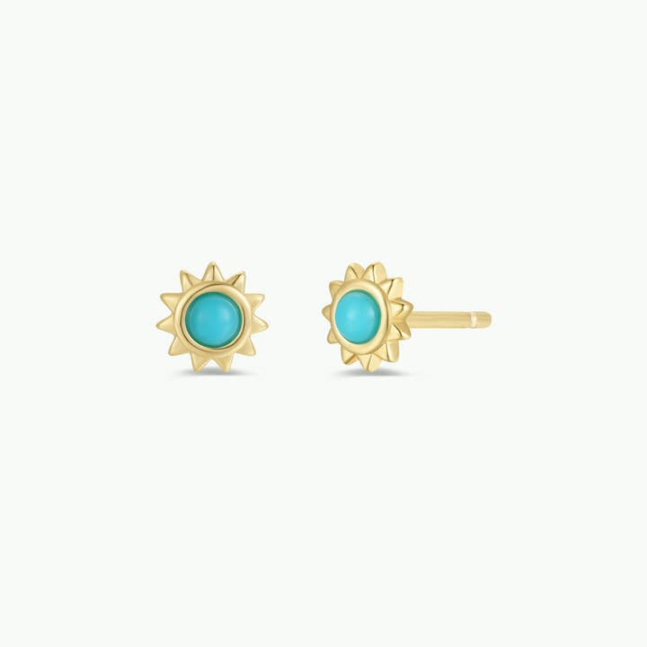 Sun Stud Earrings by JaxKelly feature gold sun-shaped studs with turquoise centers. These hypoallergenic, tarnish-free earrings add a radiant touch and are ideal for everyday wear. Displayed on a plain background.