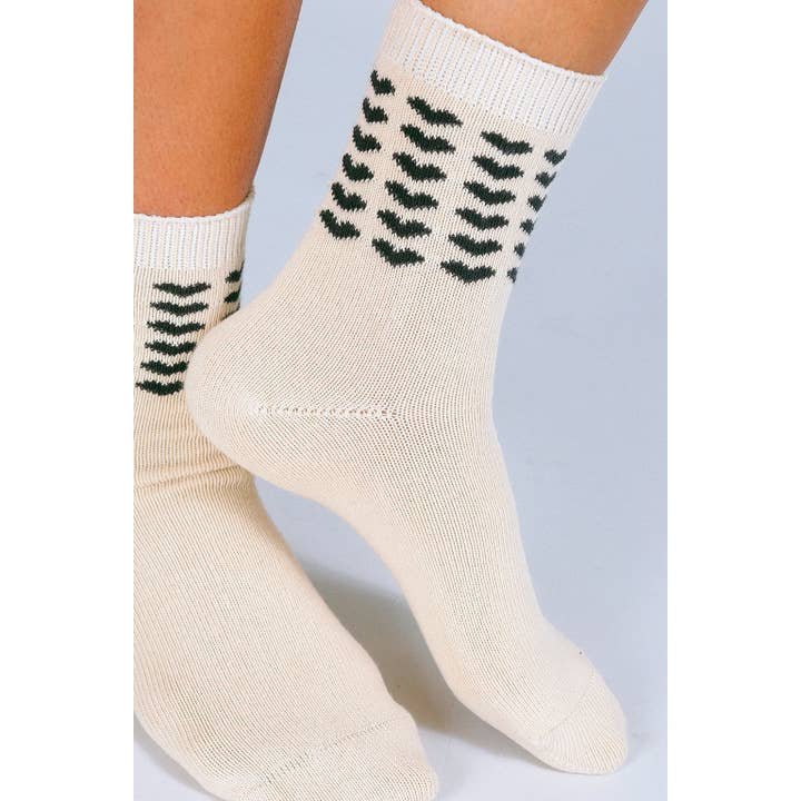 Someone wearing the Sweet Heart Ankle Sock by Tailored Union, made from premium combed cotton and detailed with a pattern of small black hearts.