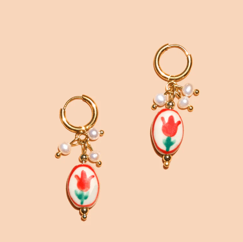 The Sweet Tulip Hoop by Peter and June features gold-plated waterproof hoops with red tulip charms and small white bead accents, displayed on a beige background.