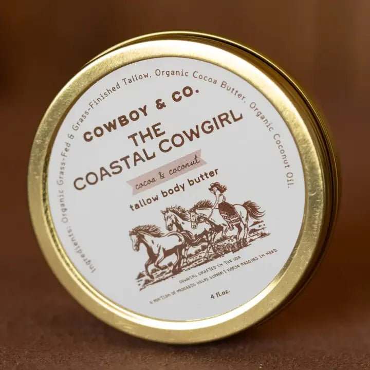 A round tin labeled "Cowboy & Co. Cocoa and Coconut Tallow Hydrating Body Butter," with art of two running horses, contains whipped body butter made with grass-fed tallow, suitable for sensitive skin.