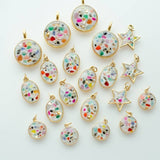 The Terrazzo Stone Necklace by Jill Makes features gold-outlined oval, round, and star-shaped pendants filled with colorful terrazzo resin, artfully arranged on a white background.