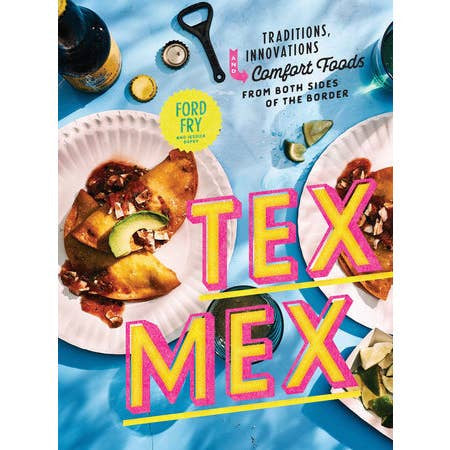 The "Tex-Mex Cookbook" by Penguin sits on a blue table, surrounded by plates of tacos, lime wedges, and drinks. The cover features comforting Tex-Mex recipes inspired by flavors from both sides of the border.