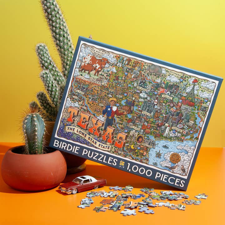 The Texas 1,000 Piece Puzzle from Birdie Puzzles is shown by a cactus in a red pot, with loose puzzle pieces and a small red toy car on a yellow surface—an ideal unique Texas gift.