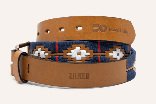 Two brown Argentine leather Zilker Belts—one engraved with "ZILKER," the other a Texas Monthly 50th Anniversary limited edition—both feature decorative stitching and patterns.