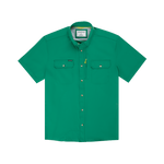 The Magnolia | Poncho by Poncho is a short-sleeve green button-up shirt with two chest pockets and a small yellow tag on the left pocket, made for breathability and shown on a white background.