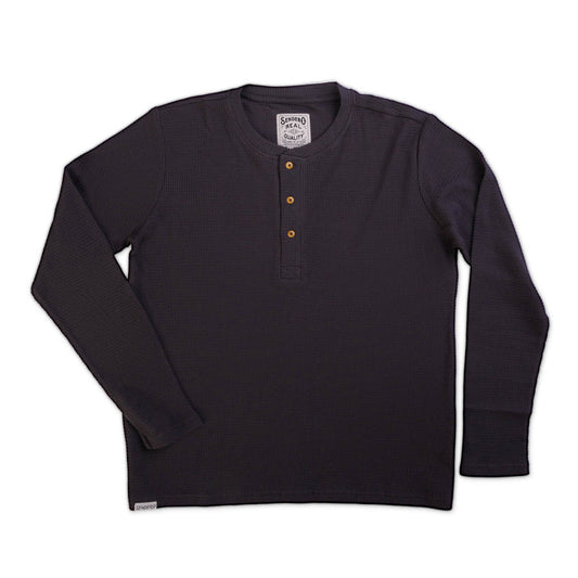 The Maverick Henley by Sendero Provisions Co. is a dark, long-sleeve waffle knit shirt with a three-button front placket, shown laid flat on a white background.