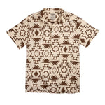 The Padre Shirt | Chama Chevron by Sendero Provisions Co. is a short-sleeved, button-up camp collar shirt featuring bold brown geometric patterns on a beige background.