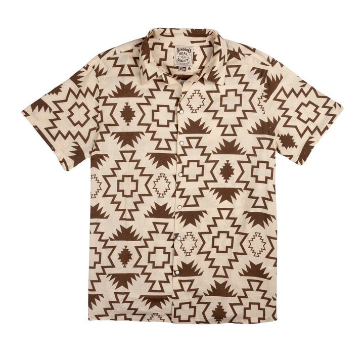 The Padre Shirt | Chama Chevron by Sendero Provisions Co. is a short-sleeved, button-up camp collar shirt featuring bold brown geometric patterns on a beige background.