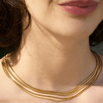 A woman shown from the neck up, lips and chin visible, wears the Thelma Layered Snake Chain necklace by Peter and June.