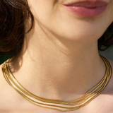 A woman shown from the neck up, lips and chin visible, wears the Thelma Layered Snake Chain necklace by Peter and June.