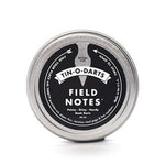 The Field Notes Tin-O-Darts is a round metal tin containing precision-cut steel Book Darts—sleek, reusable page markers ideal for marking your place in any book.