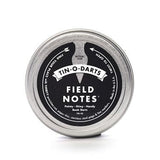 The Field Notes Tin-O-Darts is a round metal tin containing precision-cut steel Book Darts—sleek, reusable page markers ideal for marking your place in any book.