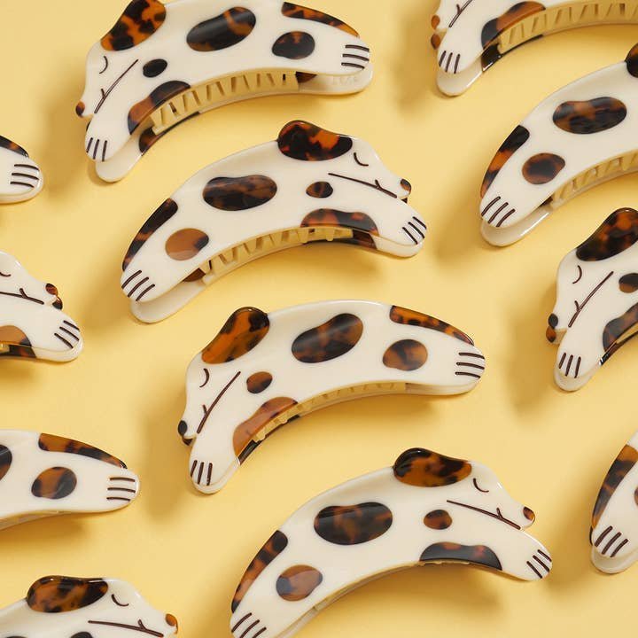 Winona Irene’s Tortie Puppy Dog Hair Claw in cream and tortoise acetate is arranged neatly on a yellow background, showcasing its unique dog-shaped design and glossy finish.