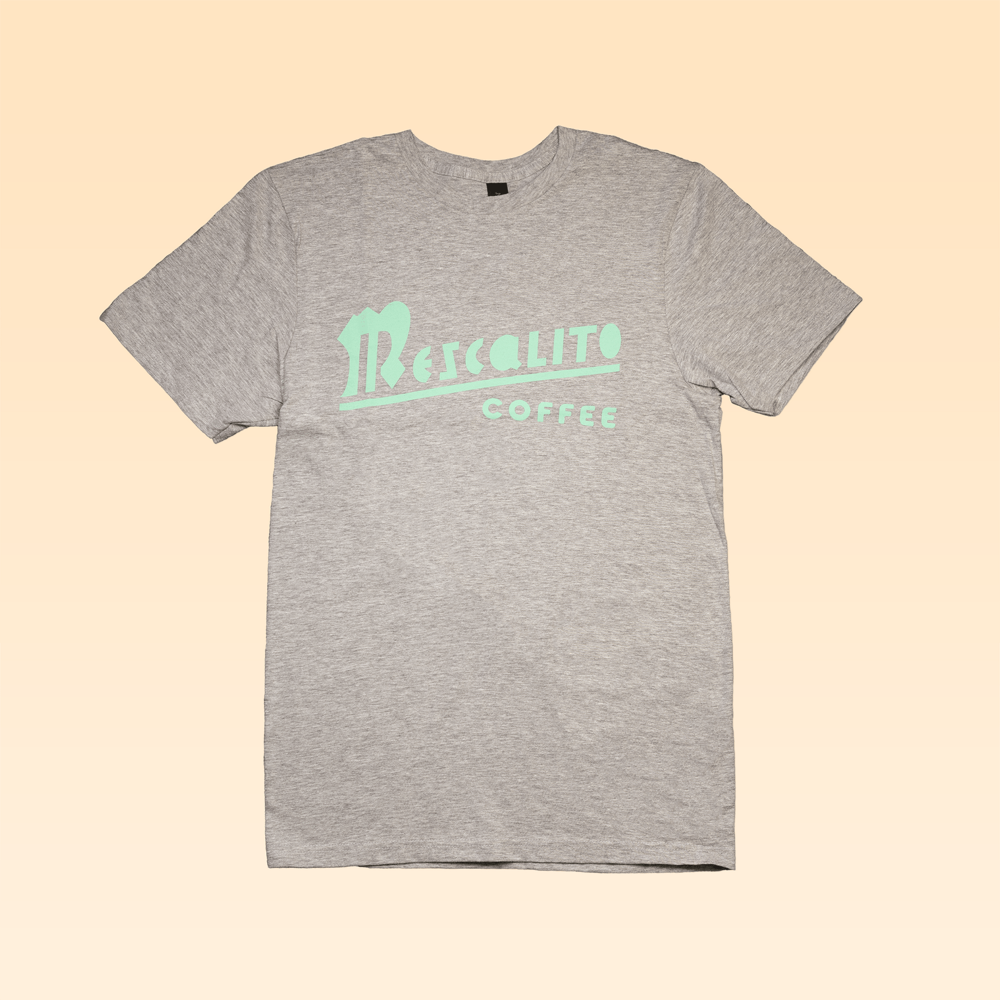 The Traditional Mescalito Marzocco Tee by Mescalito Coffee features a gray short-sleeve design with "Mescalito Coffee" in mint green on the chest, ideal for coffee enthusiasts and La Marzocco fans.