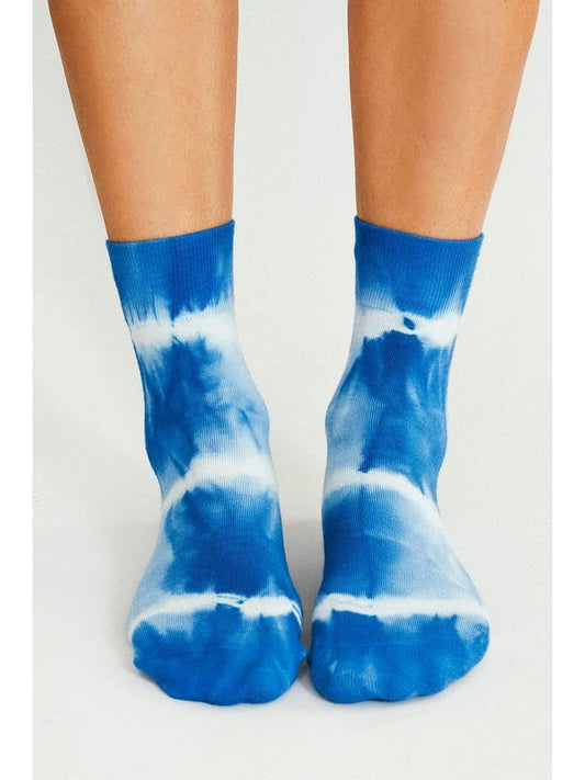 A pair of feet wearing Trippy Tie Dye Ankle Socks in blue by Tailored Union, shown from the front against a plain background.