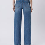 Back view of a person wearing Vervet Tummy Control Super High Rise Baggy Wide Jeans, featuring two back pockets and slight distressing, paired with white-heeled shoes.