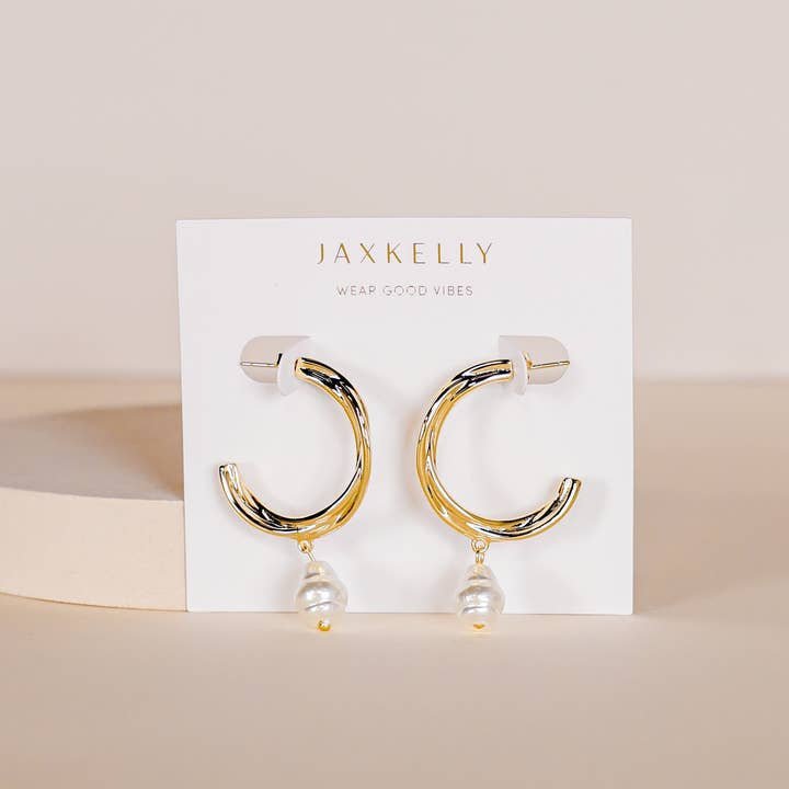 The Twisted Pearl Drop Hoop - Gold Earrings by JaxKelly feature gold-toned twisted hoops with dangling freshwater pearls, presented on a branded card. Hypoallergenic and perfect for sensitive ears.