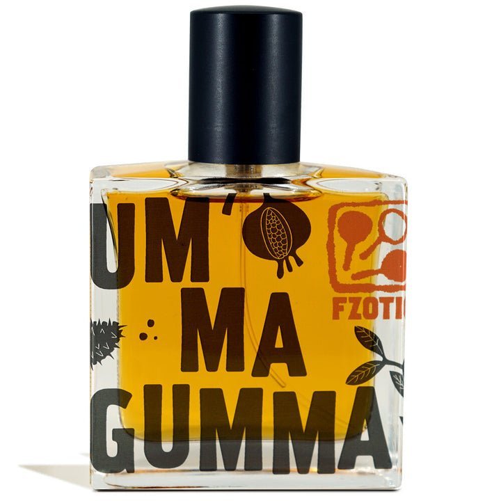 A square glass perfume bottle with amber liquid, bold black and orange "Ummagumma | Fzotic" graphics—a striking adult gourmand scent from Fzotic, featuring hints of dark chocolate.