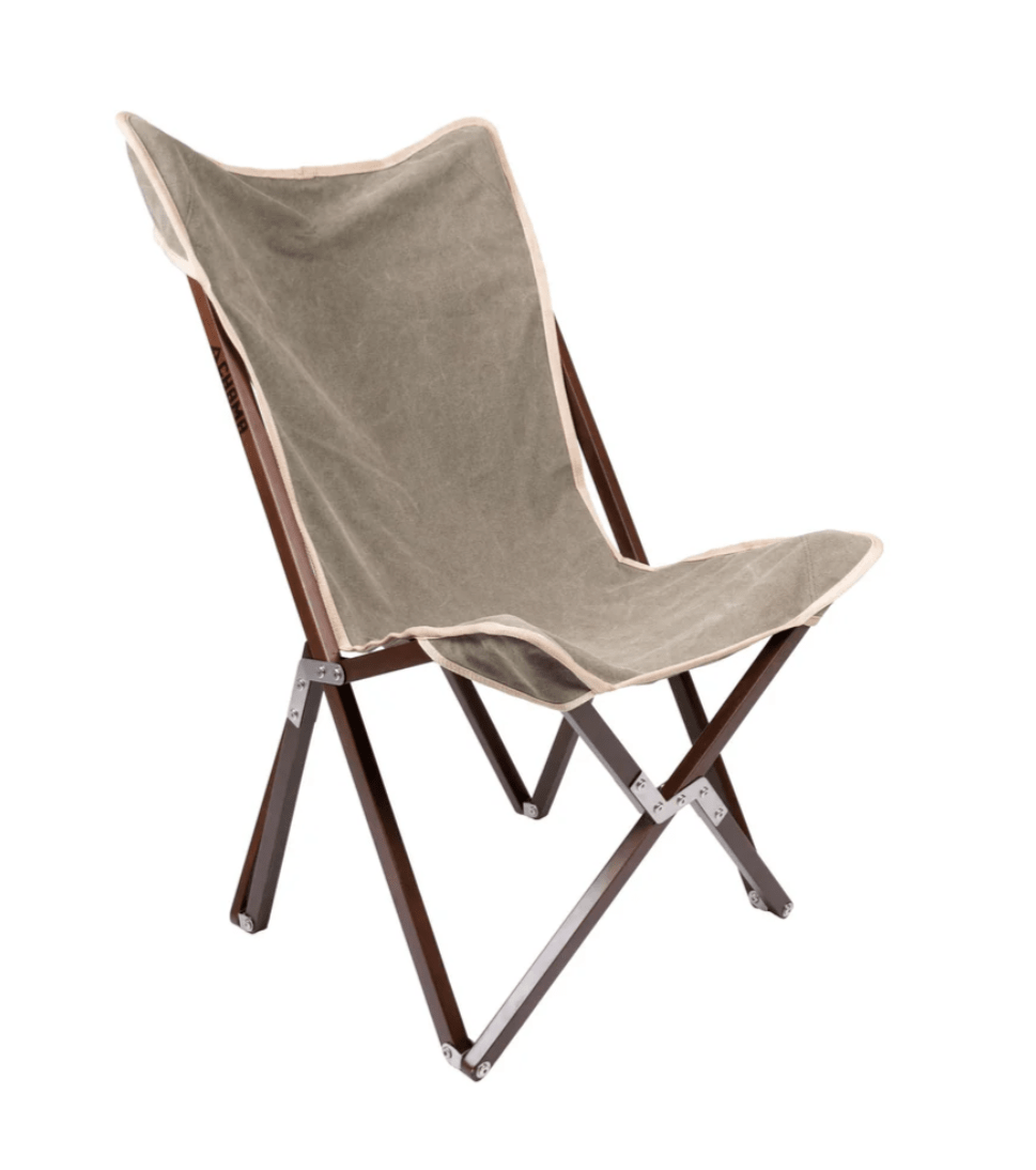 The Vaquero Chair by Chama Chairs features a brown wooden frame and beige fabric seat, displayed against a white background.