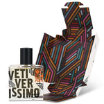 A square Vetiverissimo perfume bottle by Fzotic, labeled "VETIVERISSIMO" with a black cap, is shown beside its unfolded, patterned packaging with colorful diagonal lines, suggesting the fresh scent inside.