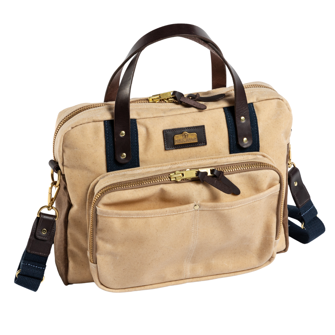 The Duck Head Waxed Canvas Laptop Bag features beige canvas, brown leather handles, gold hardware, a front zip pocket, detachable navy shoulder strap, and trolley sleeve—made in the USA and shown on a white background.