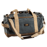 The Duck Head Waxed Canvas Overnighter Bag in charcoal, featuring tan straps, a front zipper pocket, brass hardware, and blue-gray and brown panels, is the perfect travel companion—made in the USA and shown on a white background.