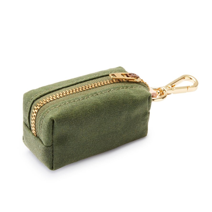 The Foggy Dog Waxed Canvas Poop Bag Dispenser is a small green pouch with a zipper and gold clasp, designed for easy, eco-friendly dog waste bag storage and convenient clean-ups on the go.