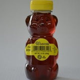 A plastic bear-shaped bottle filled with Pure Local Honey from R. Weaver Apiaries, sealed with a yellow cap and labeled "Weaver's Honey | R. Weaver Apiaries" along with product information.