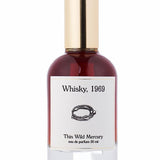 A 50ml bottle of Thin Wild Mercury’s Whisky eau de parfum, featuring a gold cap and white label with a chain design—evoking Sunset Strip rock club vibes and the smooth scent of bourbon.