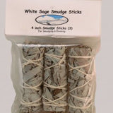 A plastic package of three 4-inch Taos Herb Co. White Sage Smudge Sticks (Salvia Apiana), wrapped with string, labeled "White Sage Smudge Stick | Taos Herb Co."—perfect for smudging and blessing.