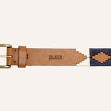 The Willie by Zilker Belts is a brown Argentine leather belt with a brass buckle, hand-stitched red, white, and navy geometric patterns, and "ZILKER" stamped at the center.