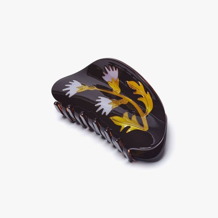 The Winona Irene Women's Milk Thistle Hair Claw in dark brown and gold acetate features a painted thistle floral design, subtly inspired by protective symbols, and is shown against a plain white background.