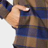 A hand with manicured nails rests in the side pocket of the W's Campfire Shacket Pintail Plaid by Duck Camp, a brown and blue plaid shirt-style jacket.