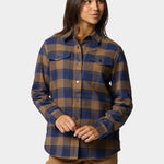 A woman stands against a plain background wearing the Duck Camp W's Campfire Shacket Pintail Plaid and tan cargo pants.